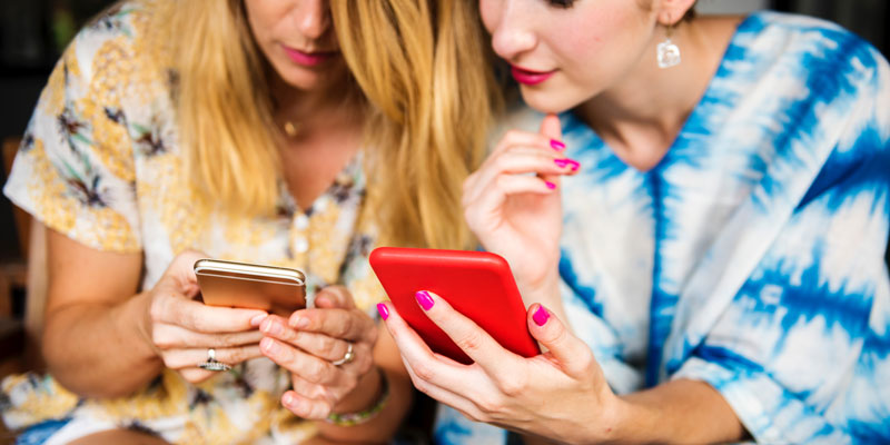 two women looking at their phones