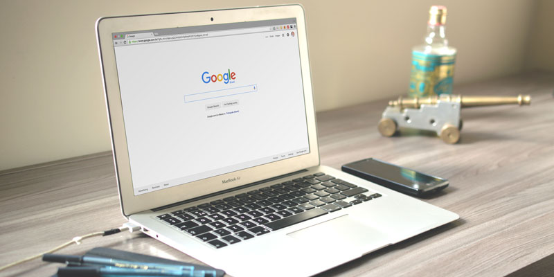 laptop with notebook, pens, cellphone, and desk toys on desk