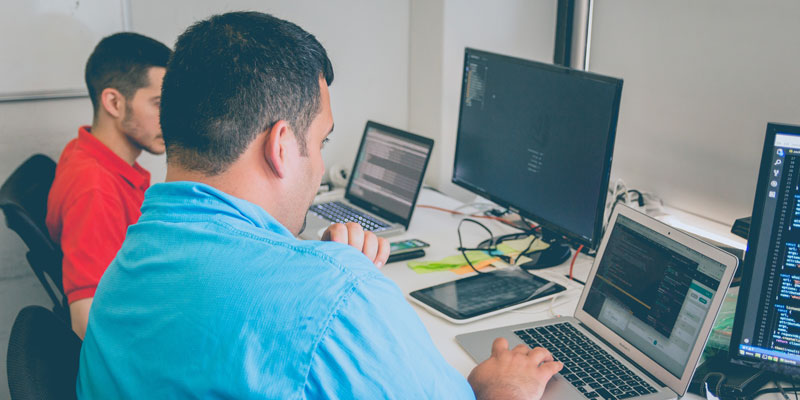 two programmers sitting in front of laptop and computer screens