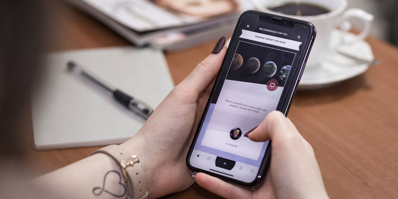 woman holding iphone x browsing web pages about space