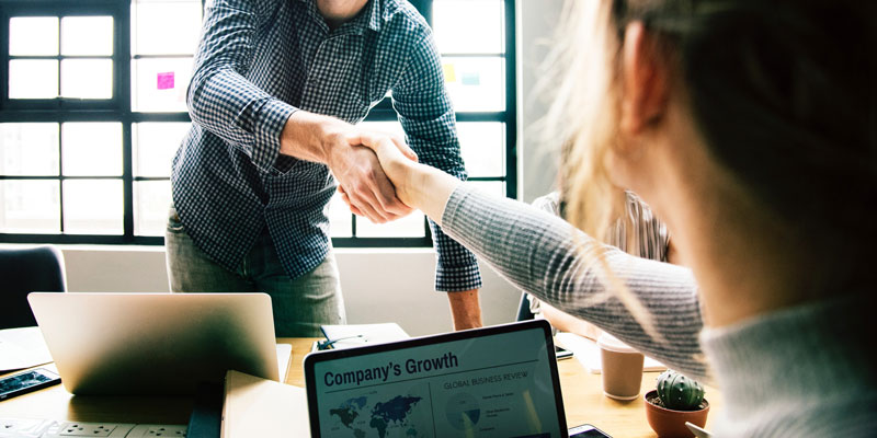 woman shaking hands with man in casual business meeting