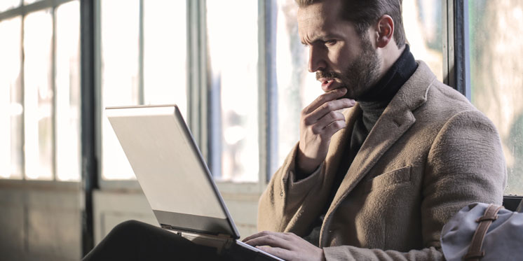 man with concentrated look working on laptop